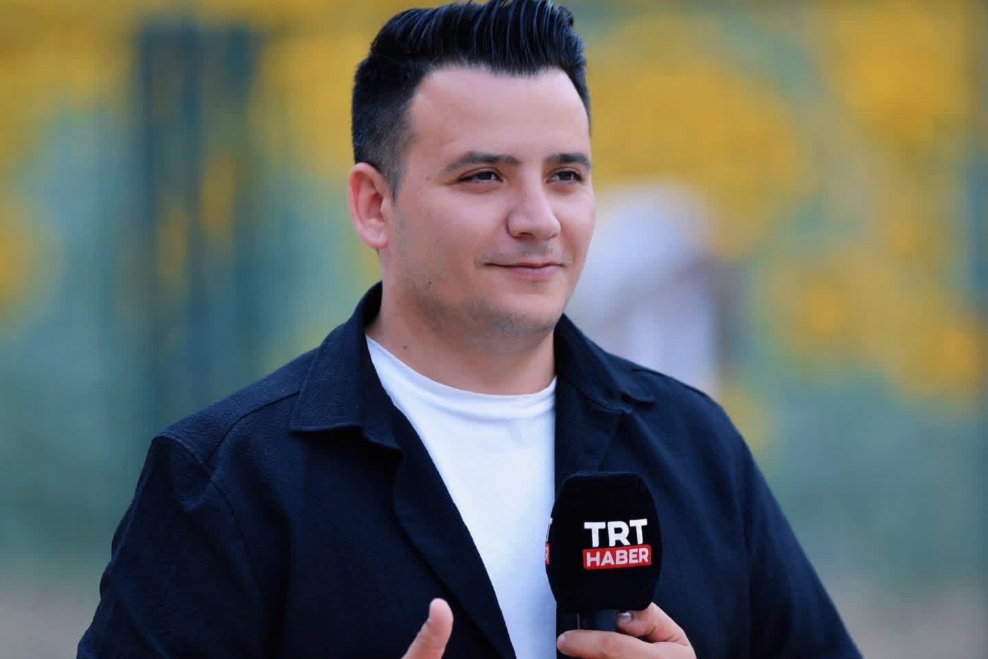 Yakup Diricanlı, elinde TRT Haber mikrofonuyla sahada habercilik yaparken.